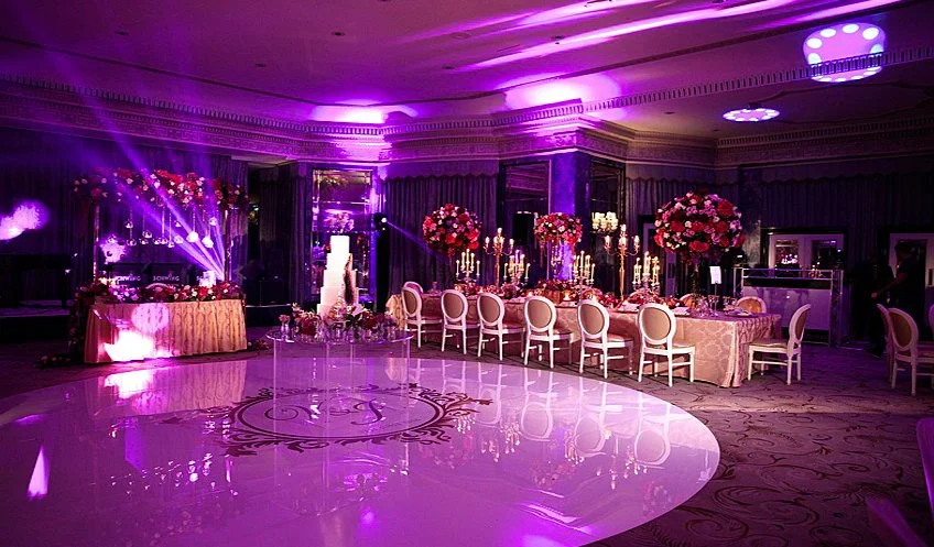 Purple-lit ballroom with a mirrored monogram dance floor